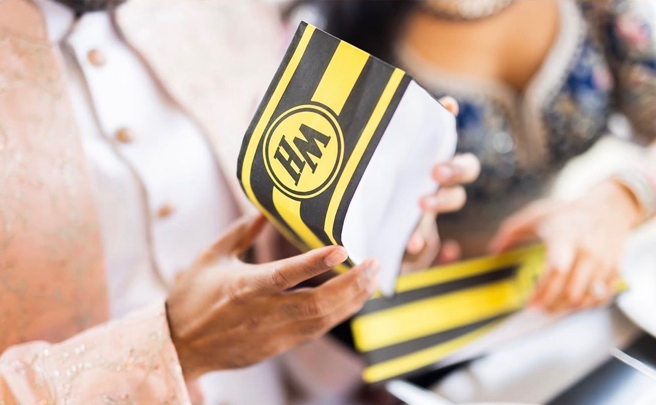 Close-up of hands holding a yellow and black diner takeout bag.